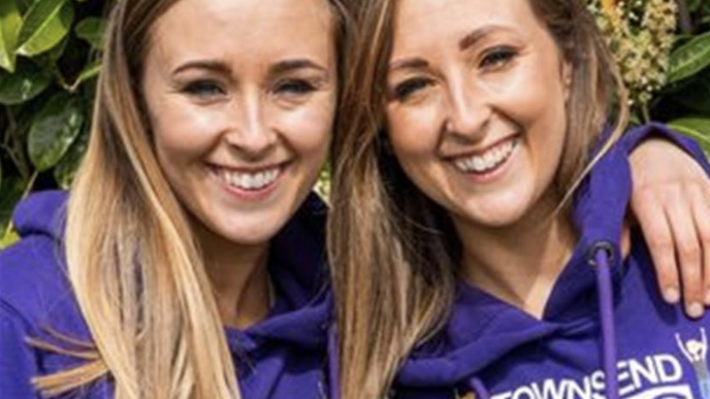 The Townsend Twins smiling wearing purple hoodies
